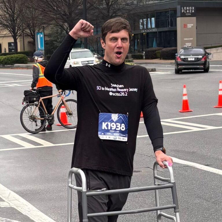 Stephen, owner of Accessible Voyages, raising a fist in celebration as he crosses a race course with his walker